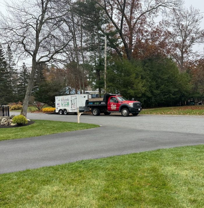 Professional landscaping crew arriving for residential landscape cleanup before winter at a well-maintained property.